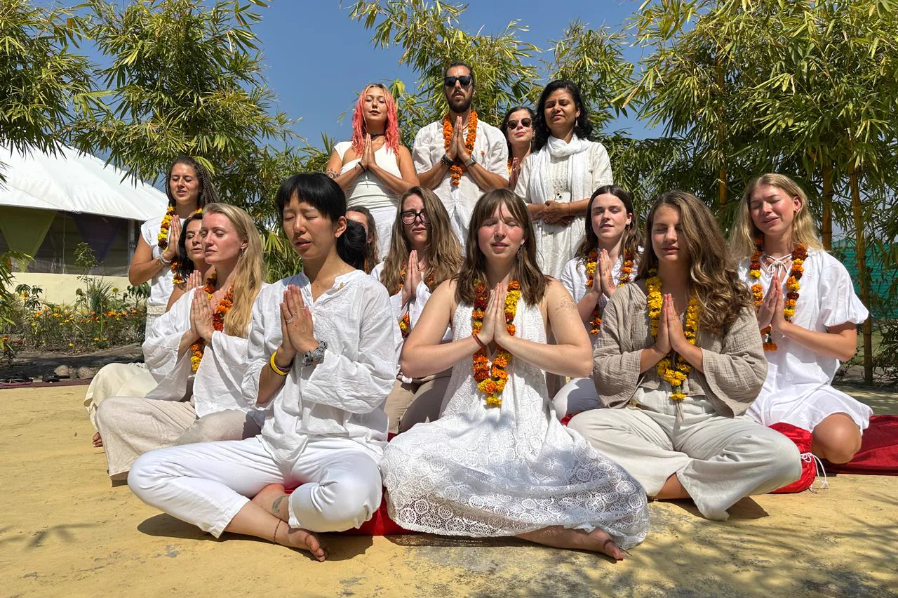 Students seated in namaste outdoors